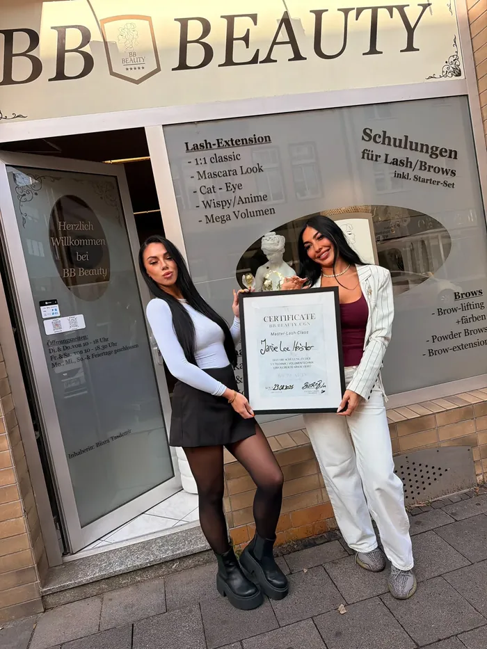 Absolventin Jamie Lee mit ihrem Zertifikat der Master Lash Class vor dem Studio