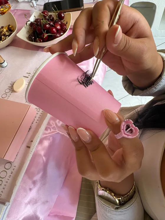 Übung mit der Pinzette: Wimpernfächer auf einem rosa Becher